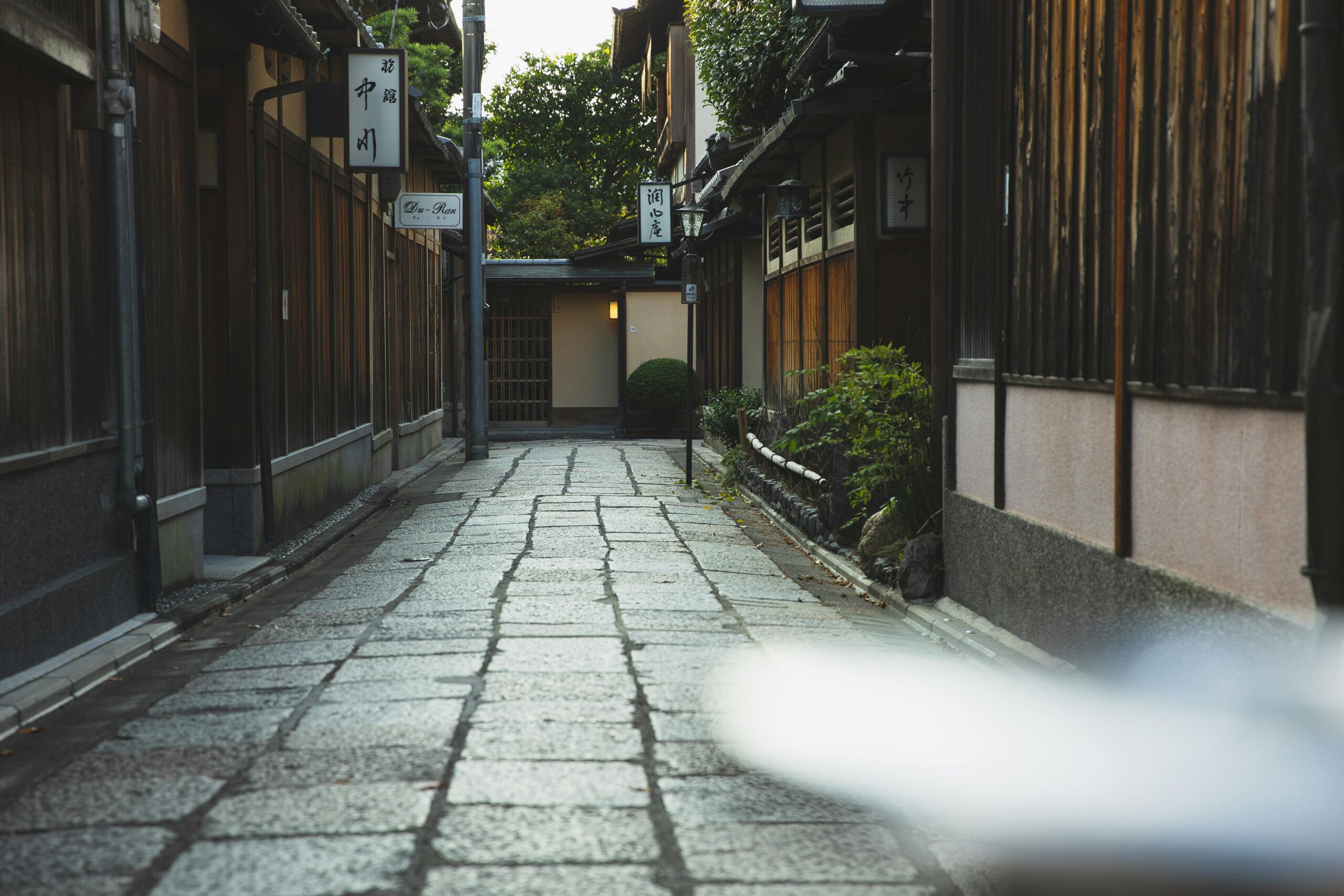 Explore a serene alleyway in Kyoto, Japan, showcasing traditional wooden architecture and cultural heritage.